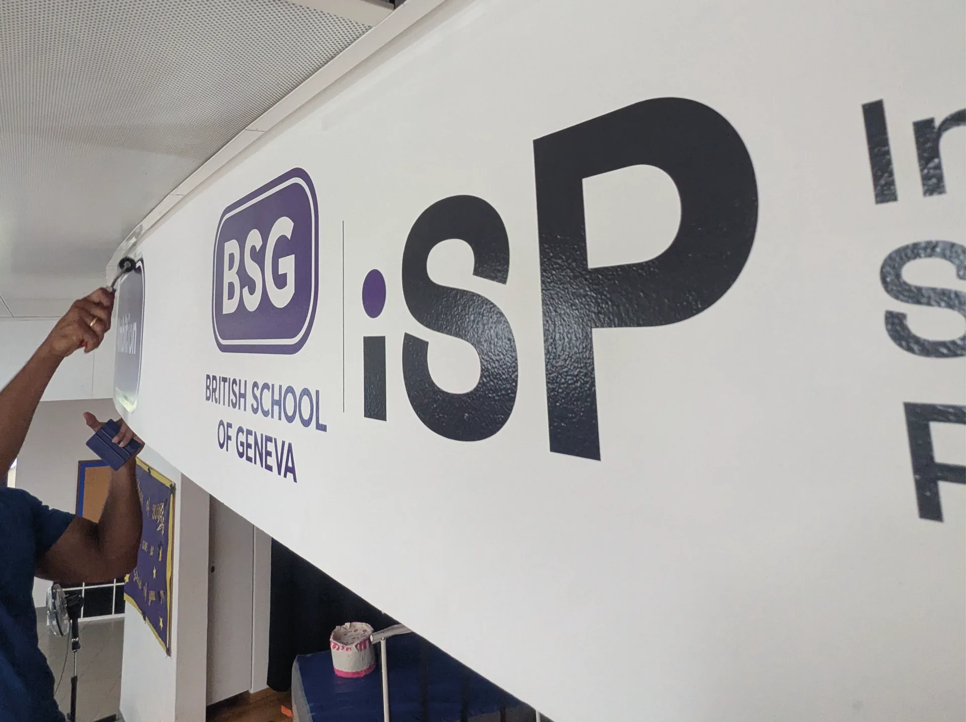 British School — Pose à la raclette du logo BSG · iSP en adhésif découpé sur le bandeau d’entrée de l’école