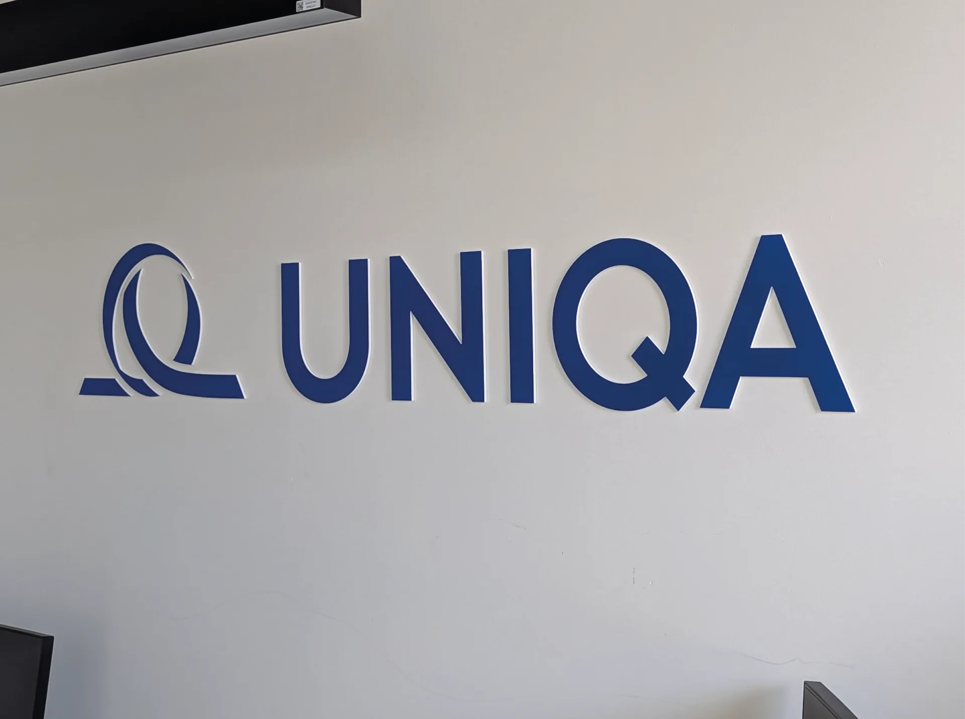 UNIQA — Logo UNIQA en lettres relief bleues posé sur le mur de la réception